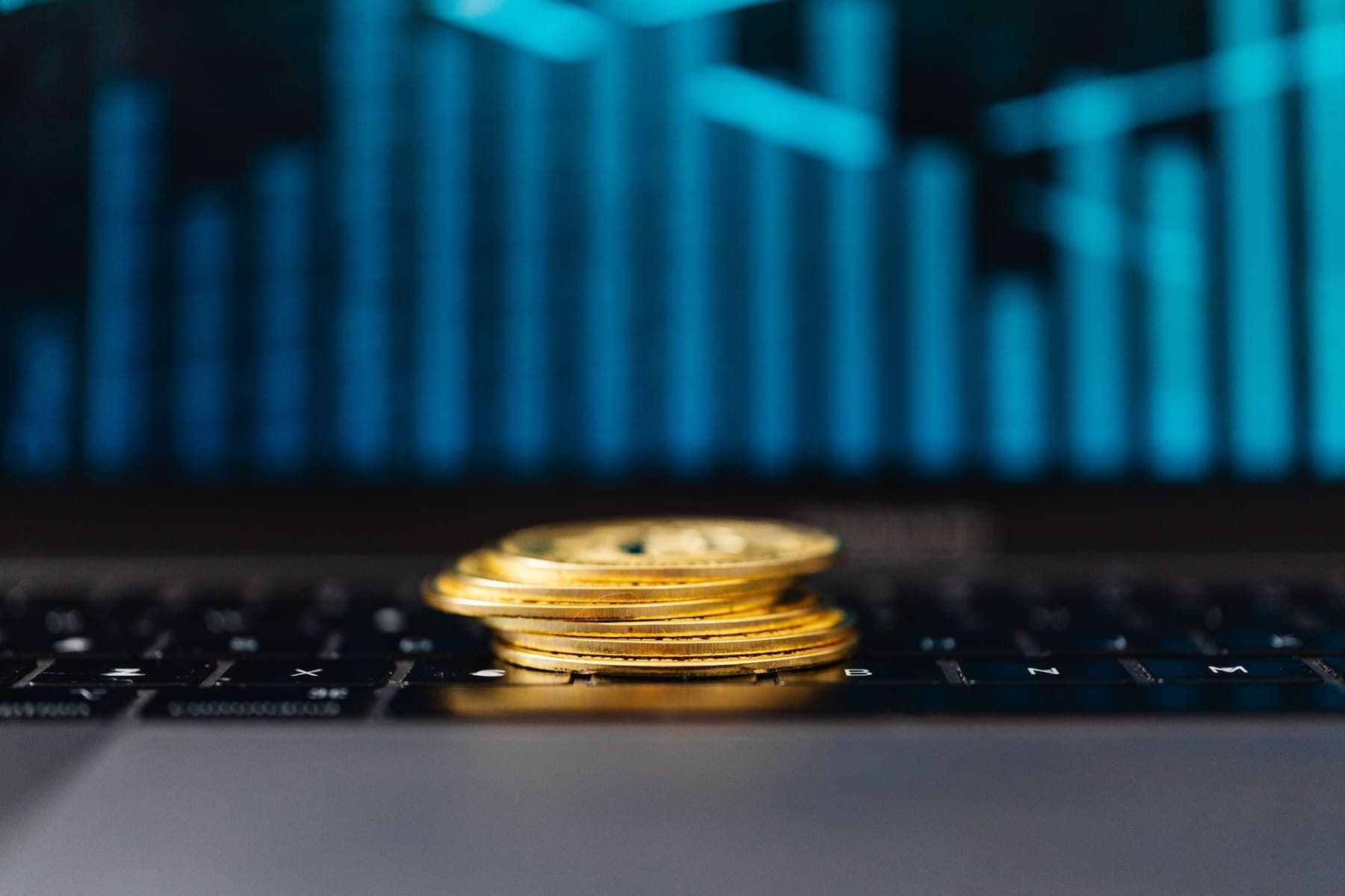 Gold coins on a laptop showing a price chart