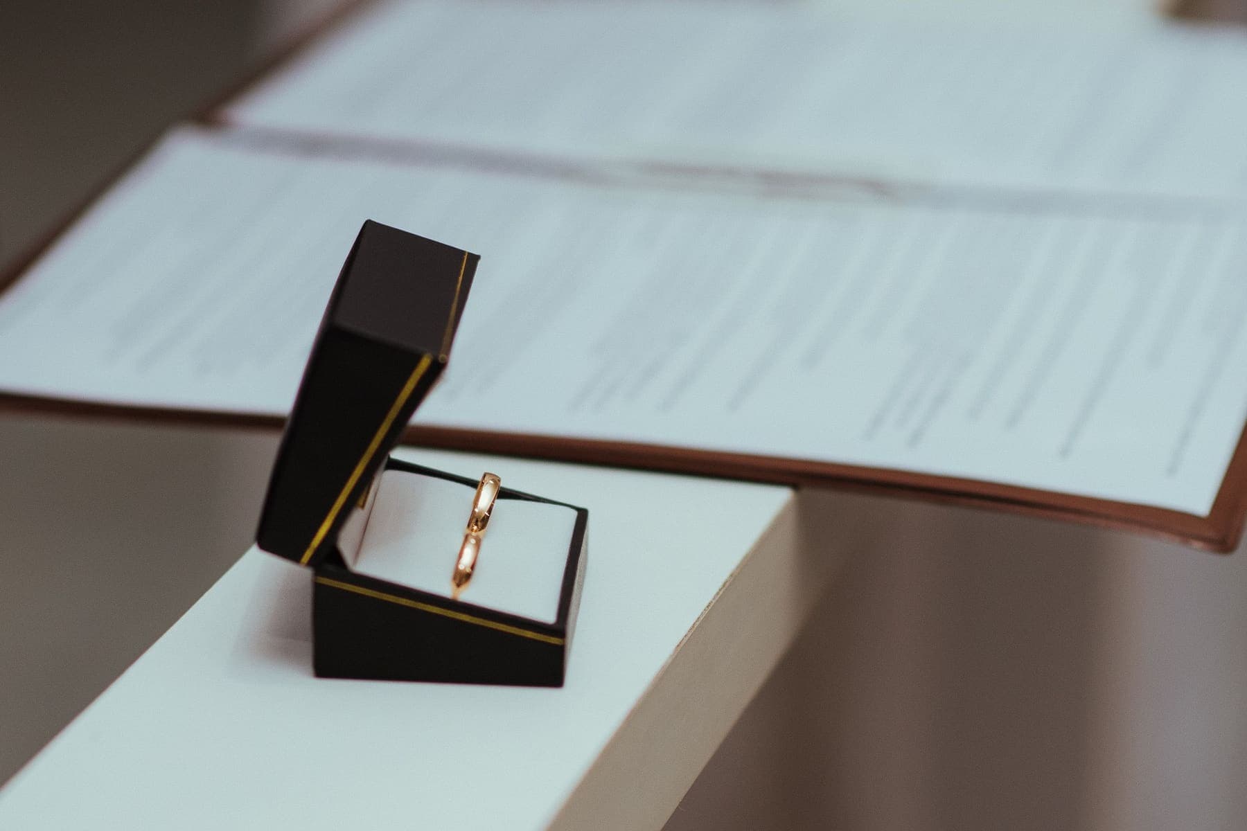 Gold rings in a box next to paperwork