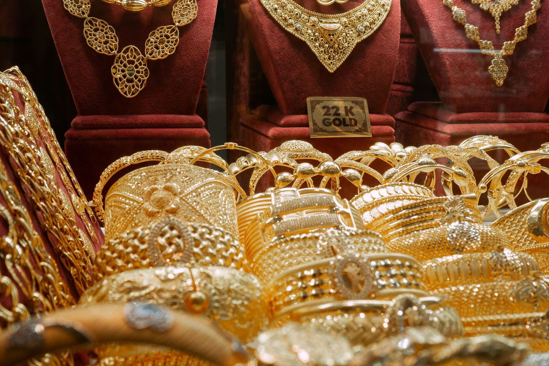 Gold necklaces on busts above rows of bangles